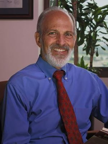 Larry Colley looking at the camera in a blue shirt and red tie