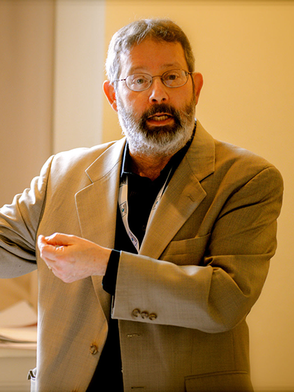 Ken teaching wearing a khaki coat pointing to something left of the camera