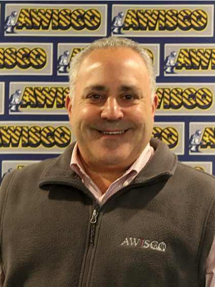 Lloyd in front of an nAWISCO branded wall smiling with a pink shirt and a grey vest