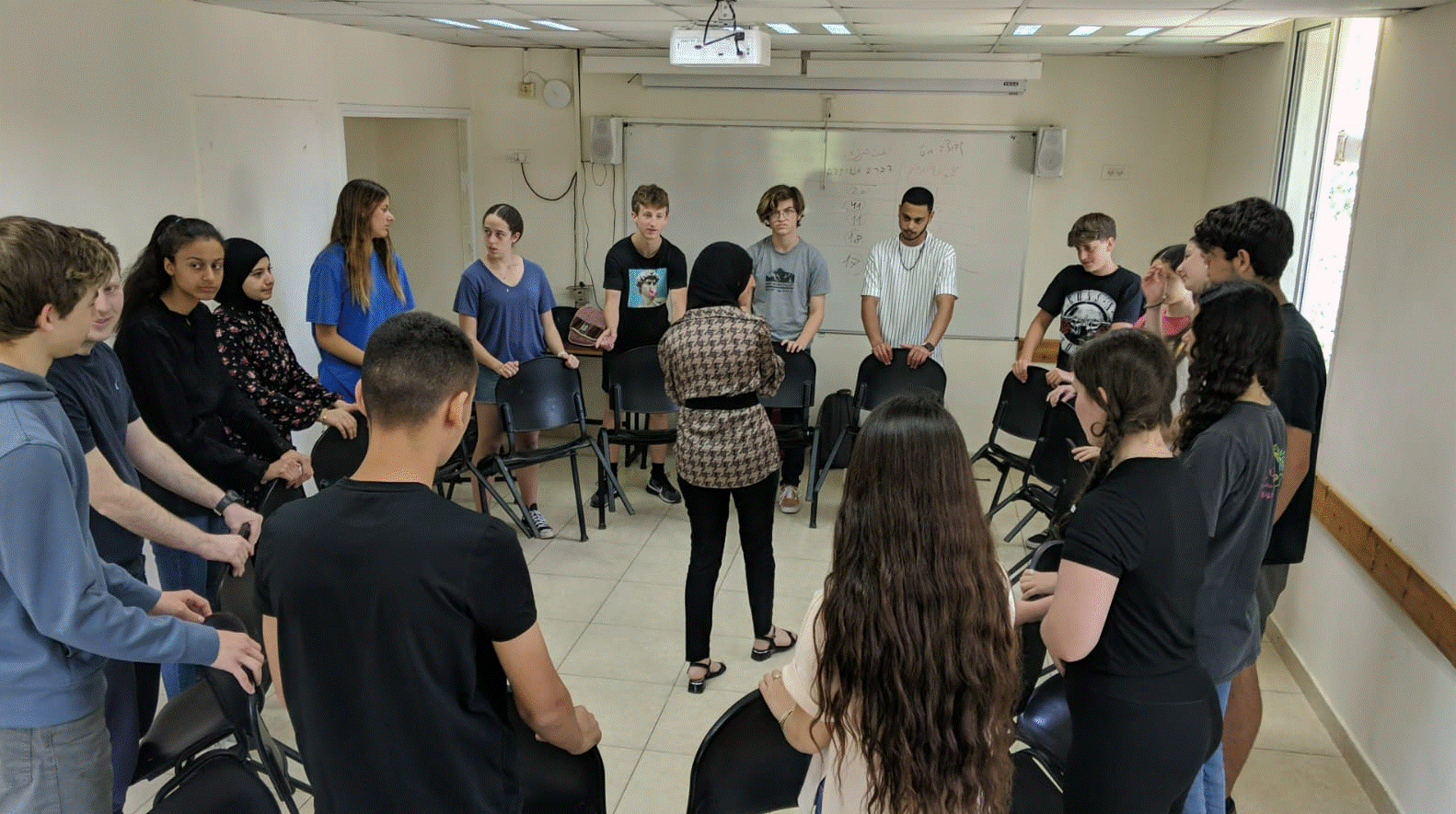 Participants standing around chairs engaged in an activity together