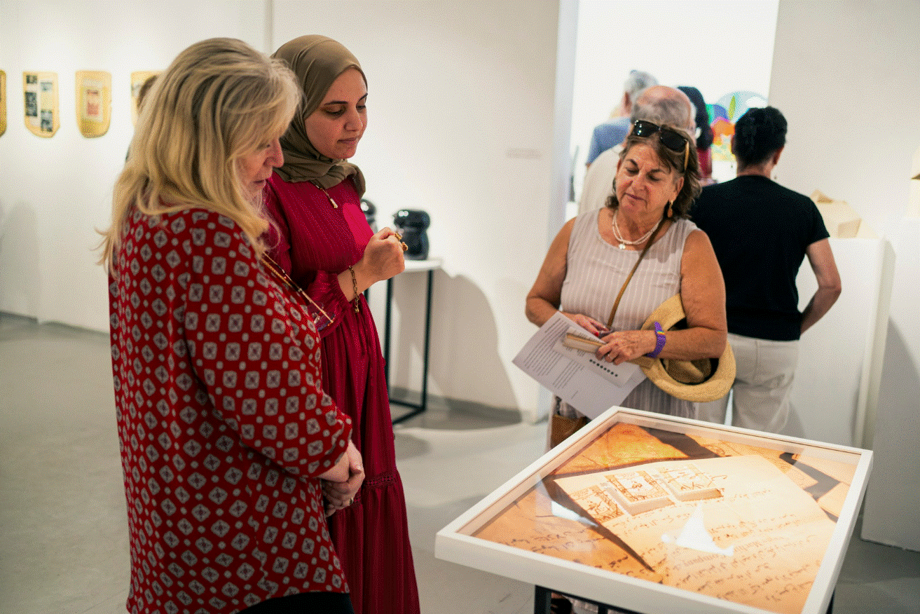 three people looking at am art piece on a table 