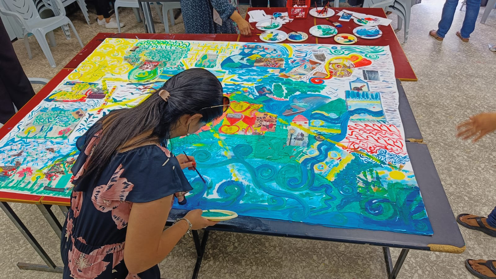 a woman painting  on a large canvas with blue