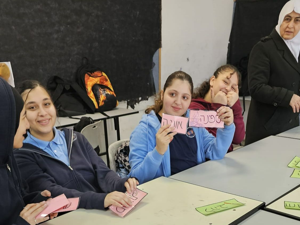 Students showing cards with hebrew writing on them to one another