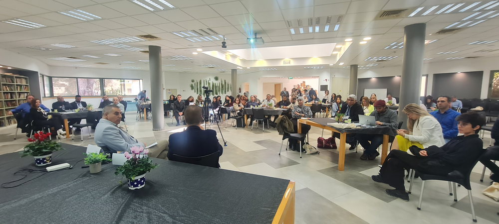 Around 35 People seated in chairs in a meeting room