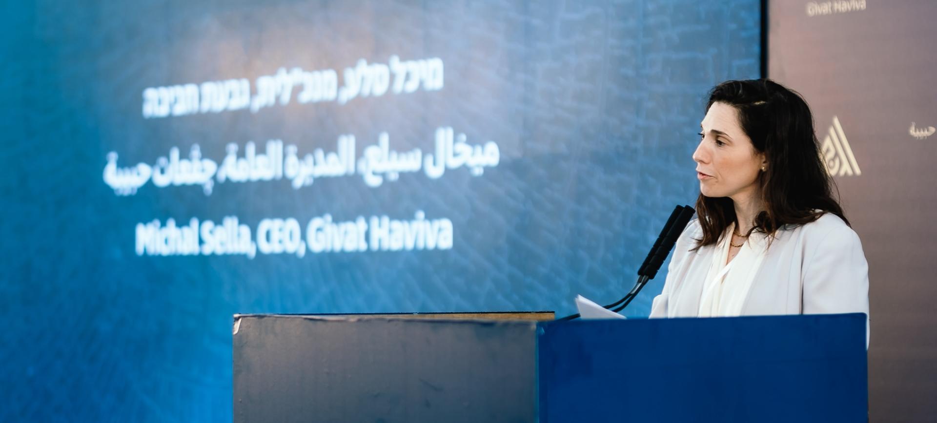 Michal Sella, CEO speaking into a microphone behind a podium
