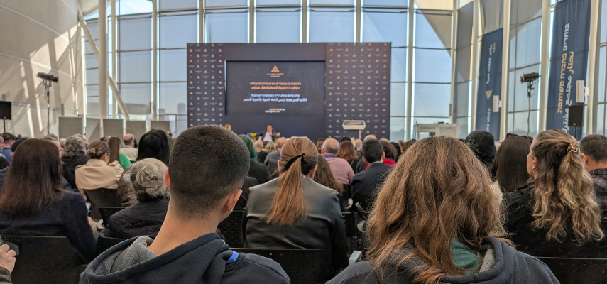 People sitting in a conference facing the speaker at the front