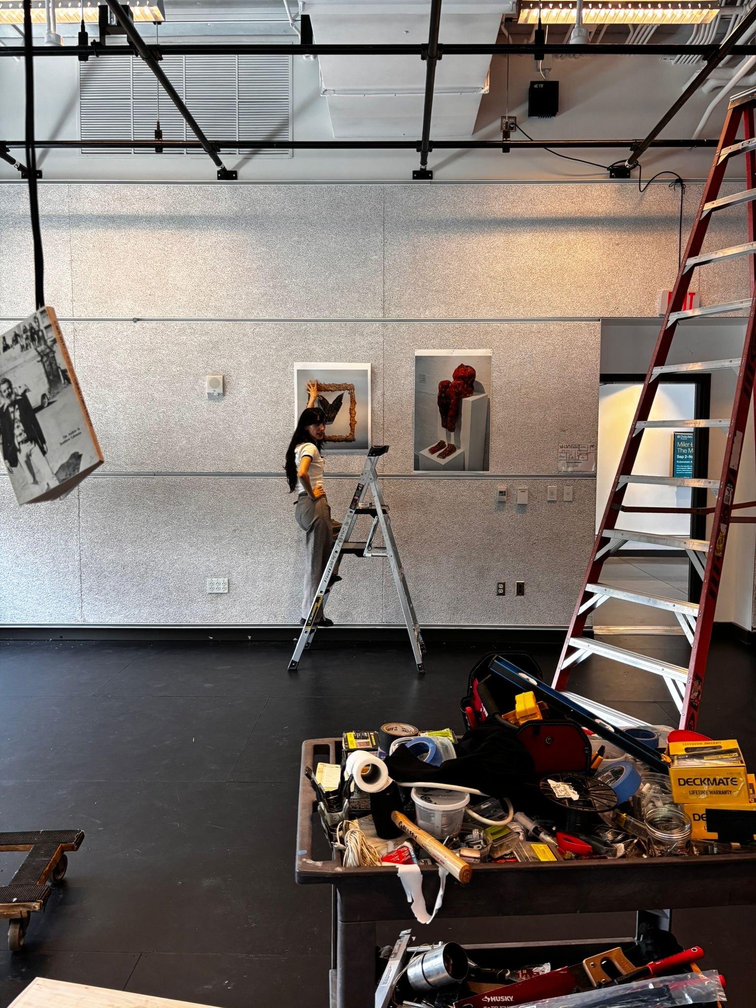 Malak Manzour hangs her art pieces for an exhibition at Duke University. The five Israeli Arab and Jewish Artists brought selections of art they created at Givat Haviva.