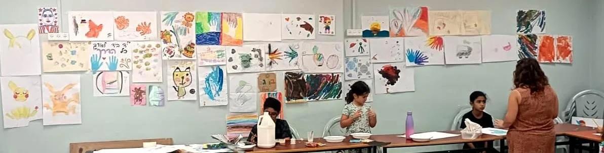 Children standing below artwork hanging on a wall