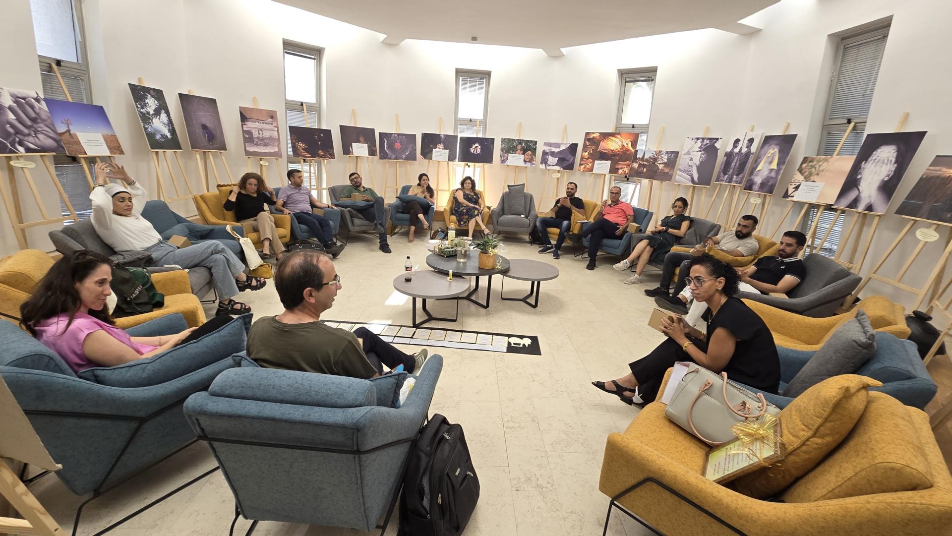 People sitting around in a circle with artwork on the walls